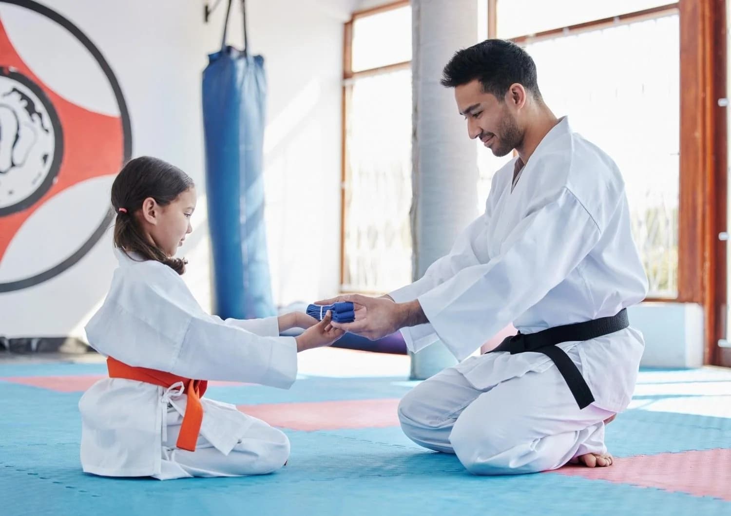 martial arts school instructor interacting with one of his students while handing over a belt