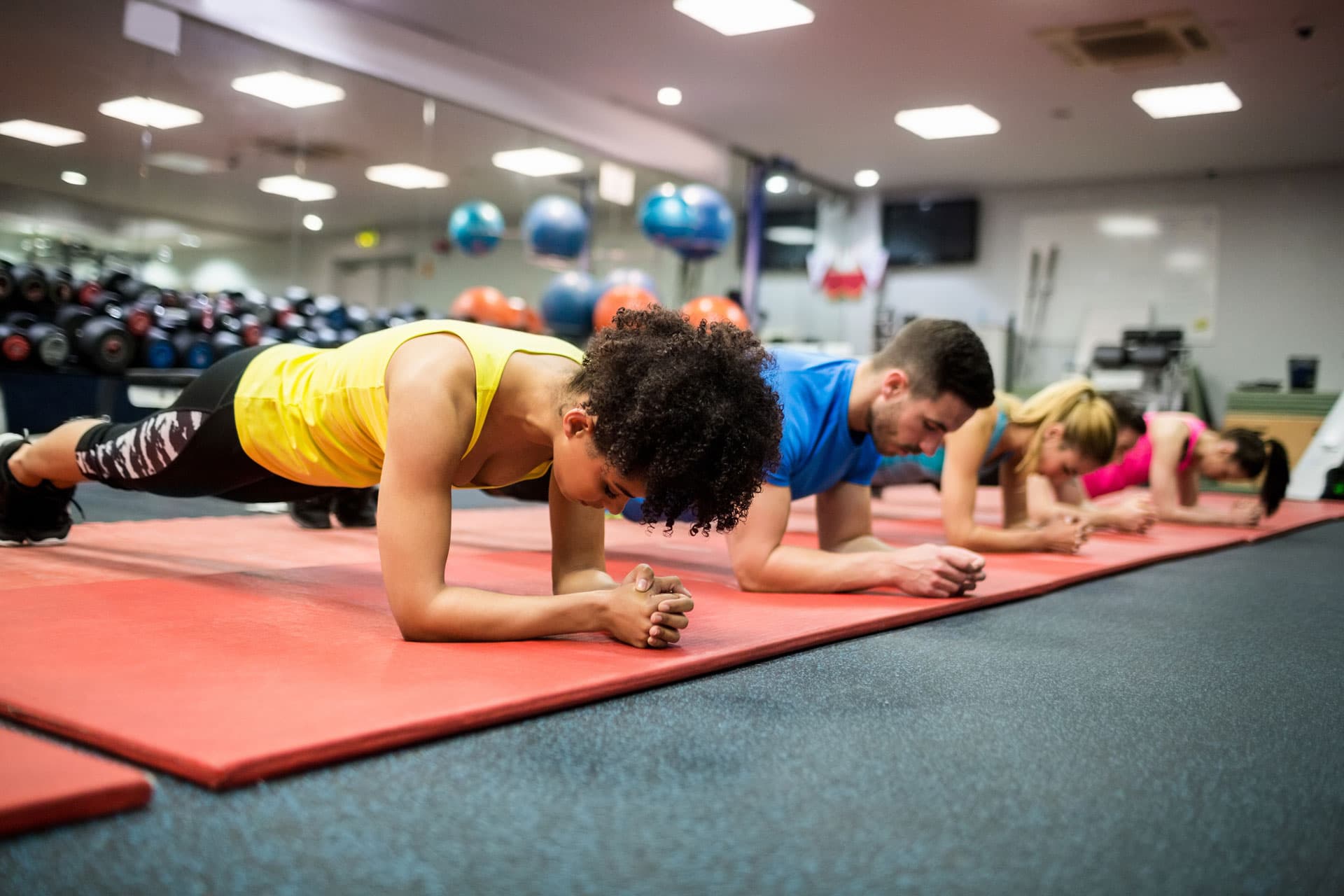 Group fitness class performing planks on exercise mats during a strength and conditioning workout.