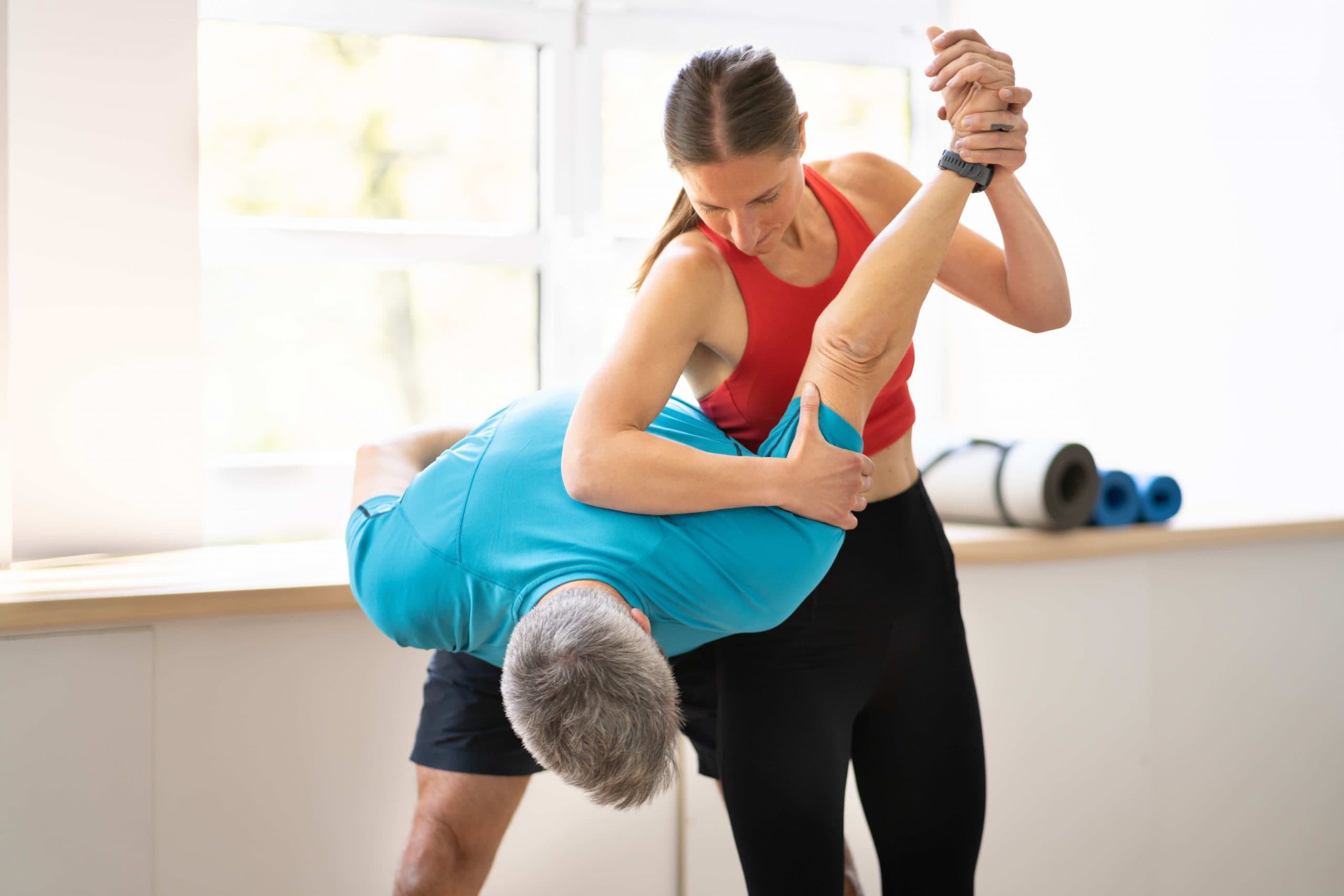 Personal trainer assists a client with a deep upper-body stretch during a guided fitness session.